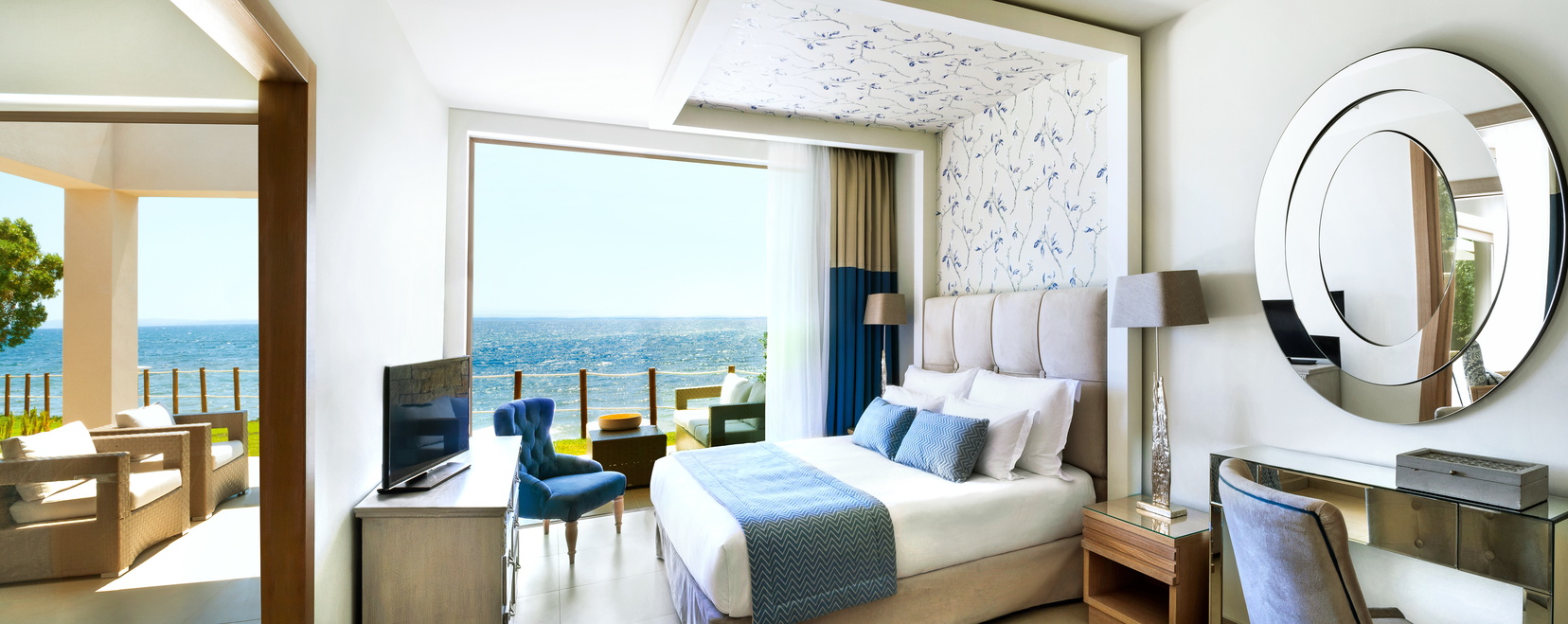 Two bedroom bungalow suite with a beachfront view at the Ikos Olivia with large double bed, television and doors opening onto a terrace balcony looking over the sea