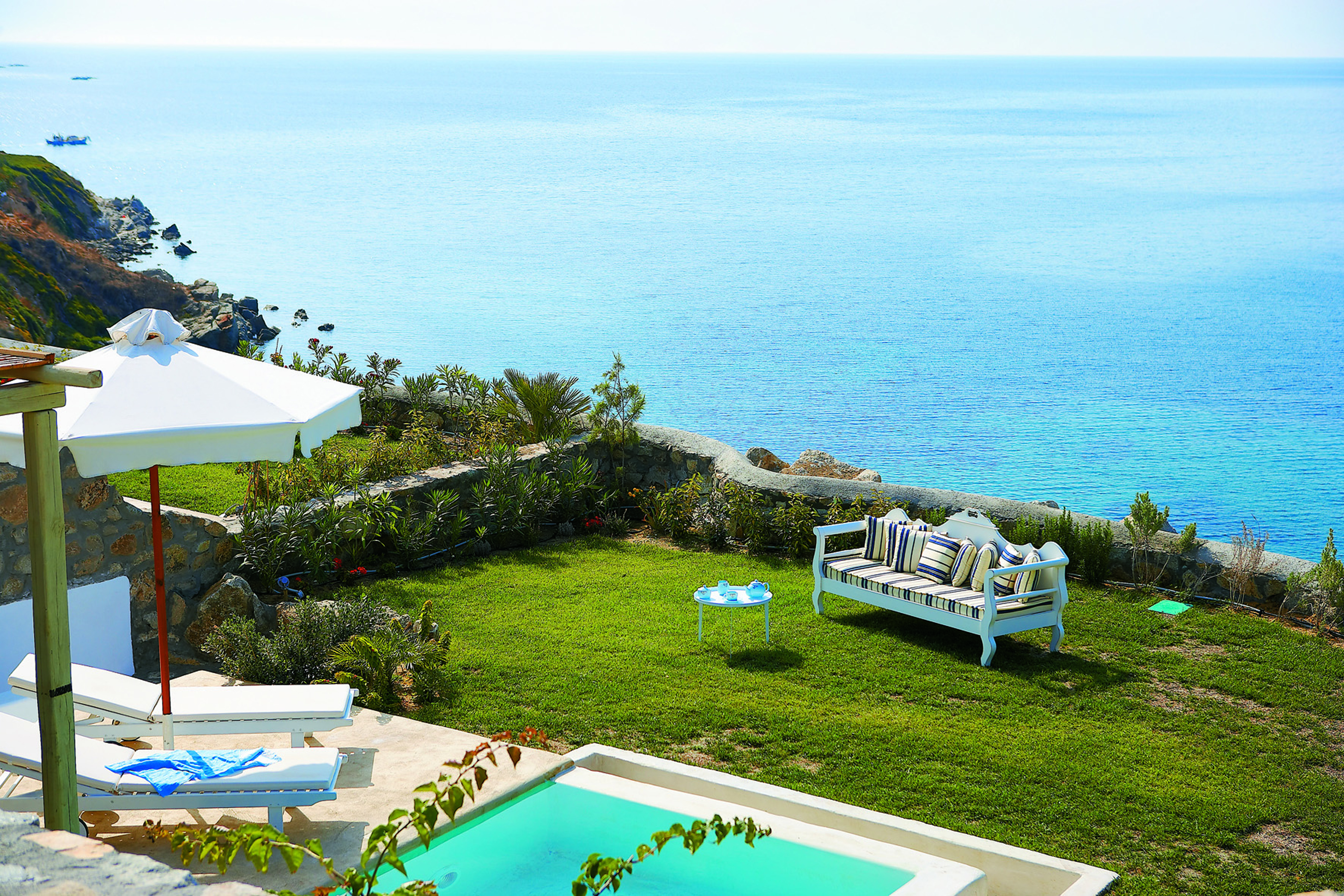 Mykonos Blu Greece Grecotel private terrace view pool with sun loungers and umbrella garden area and sofa