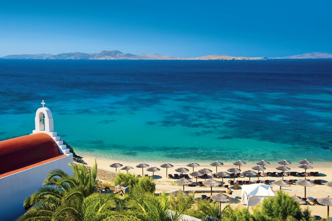 Mykonos Grand Hotel Greece beach white church with terracotta roof overlooking beach with umbrellas