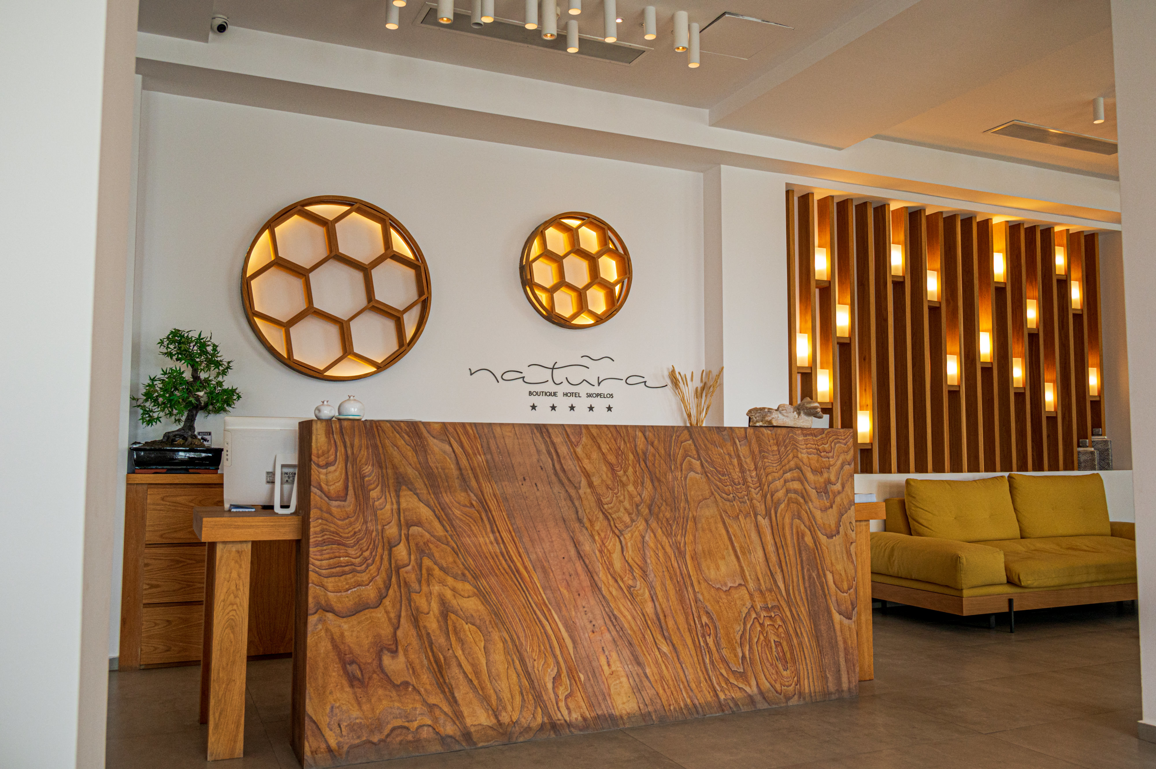 Natura Luxury Boutique Hotel reception desk made of a single piece of wood, with lighting scattered on wall behind in geometric honeycomb pattern