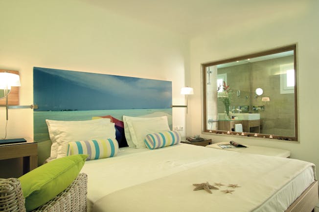 Petasos Beach Resort Greece design suite bedroom with picture of beach behind bed and window into bathroom