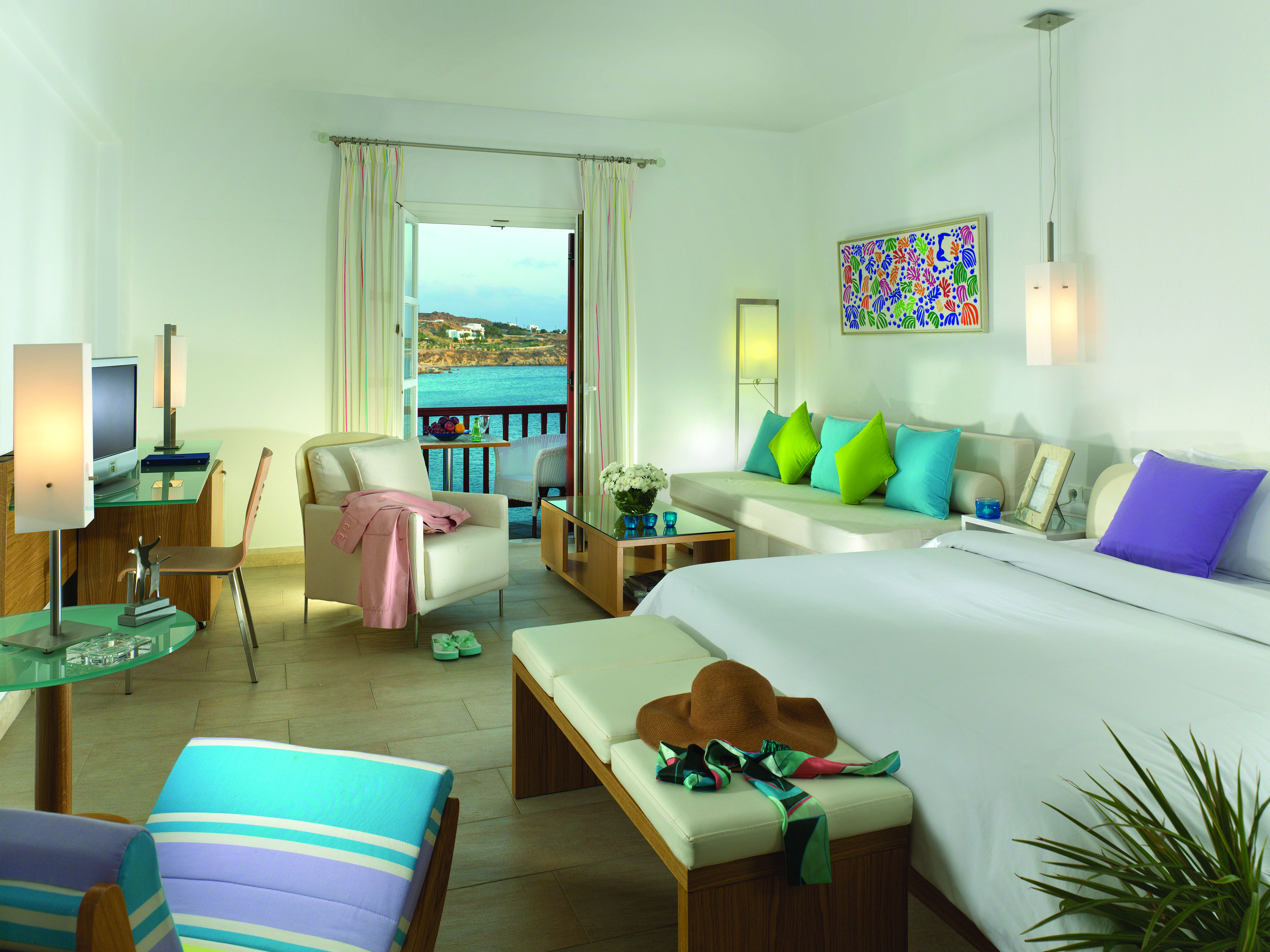Petasos Beach Resort Greece suite with large white bed and seating area and view to balcony with sea view