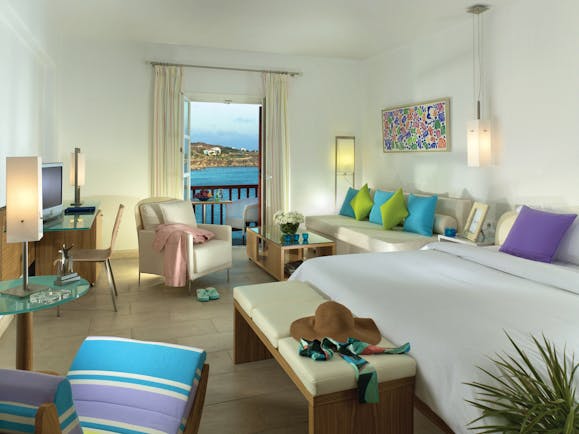 Petasos Beach Resort Greece suite with large white bed and seating area and view to balcony with sea view