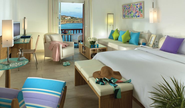 Petasos Beach Resort Greece suite with large white bed and seating area and view to balcony with sea view