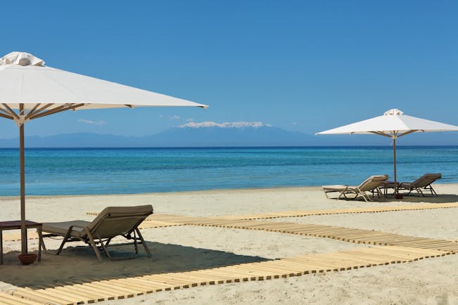 Porto Sani Greece beach with sun loungers and white umbrellas