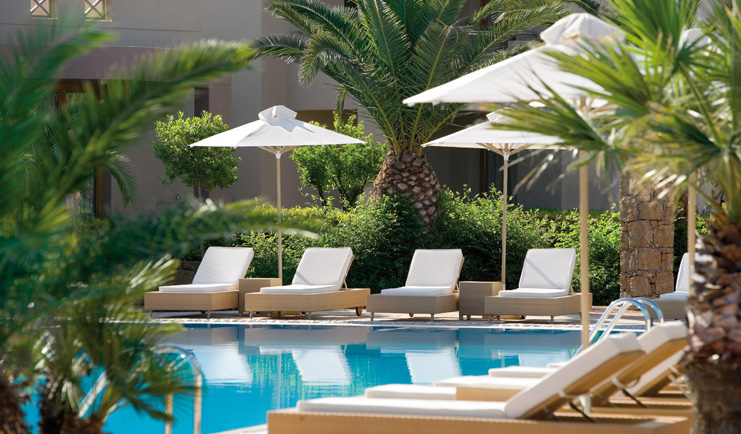 Porto Sani Greece poolside outdoor pool sun loungers palm trees