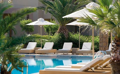 Porto Sani Greece poolside outdoor pool sun loungers palm trees