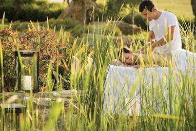 Porto Sani Greece spa man giving a woman a massage in a garden area 
