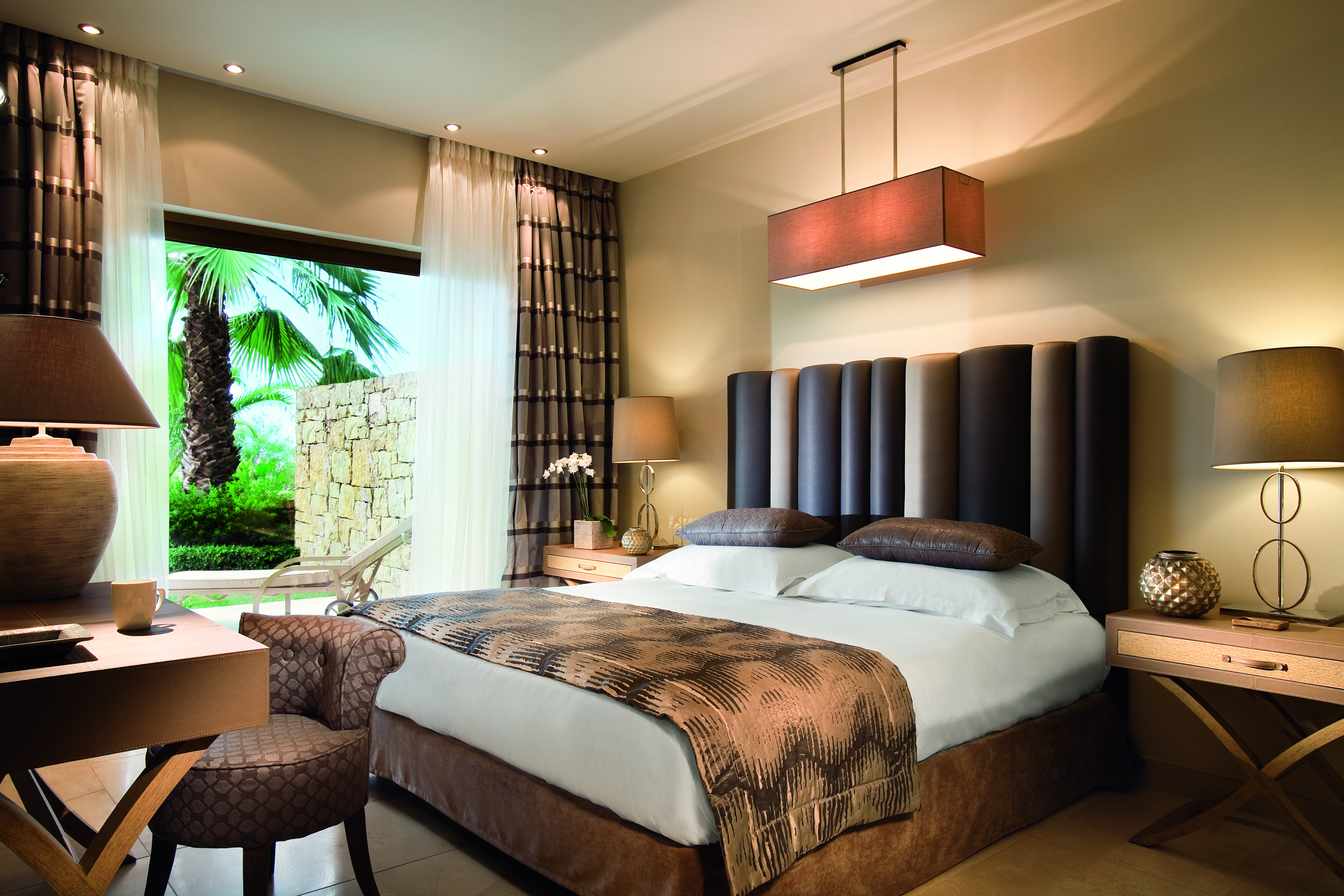 Sani Asterias Greece suite with large bed and sitting area with chair and view to private terrace