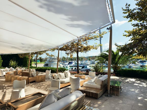 Sani Asterias Greece terrace outdoor lounge area with sofas next to boats docked in marina