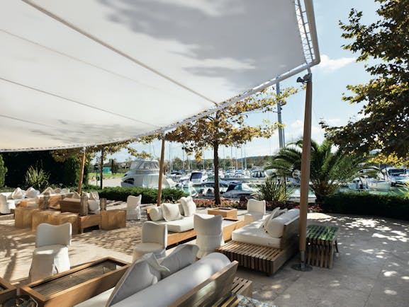Sani Asterias Greece terrace outdoor lounge area with sofas next to boats docked in marina