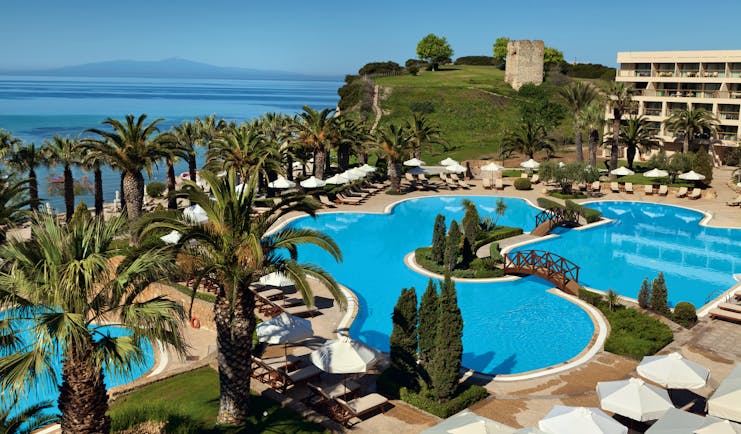 Overview of the main pool at the Sani Beach with palm trees surrounding the blue pool