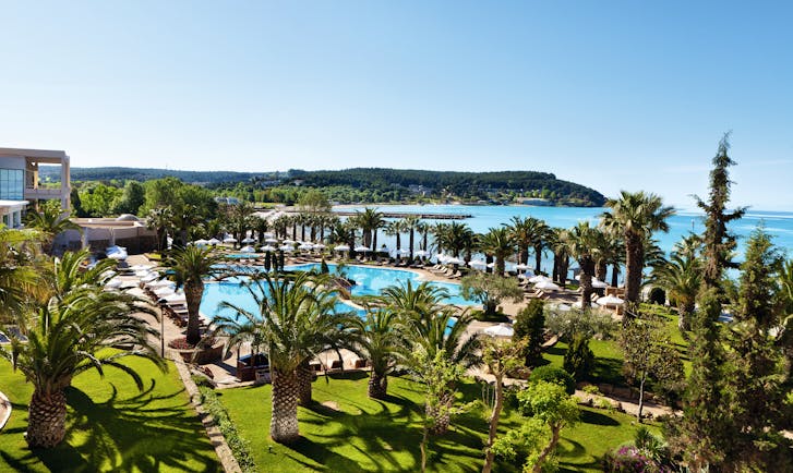 View of the Sani Beach pool from above with grassy areas and palm trees surrounding the pool