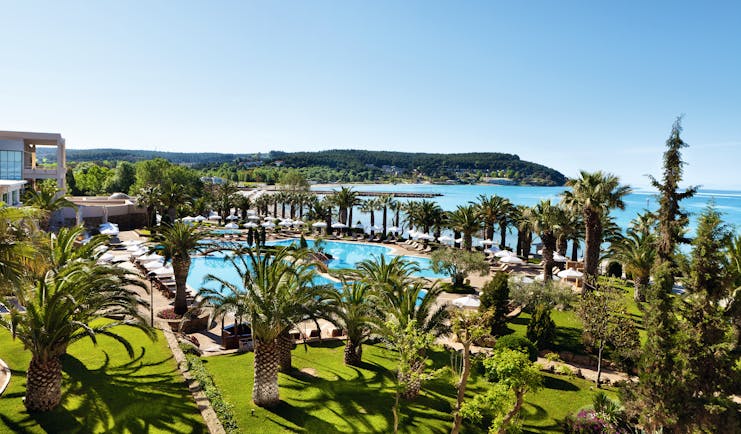View of the Sani Beach pool from above with grassy areas and palm trees surrounding the pool