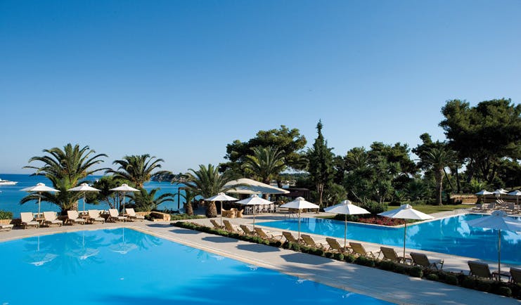 Sani Club Greece outdoor pool loungers umbrellas palm trees sea view