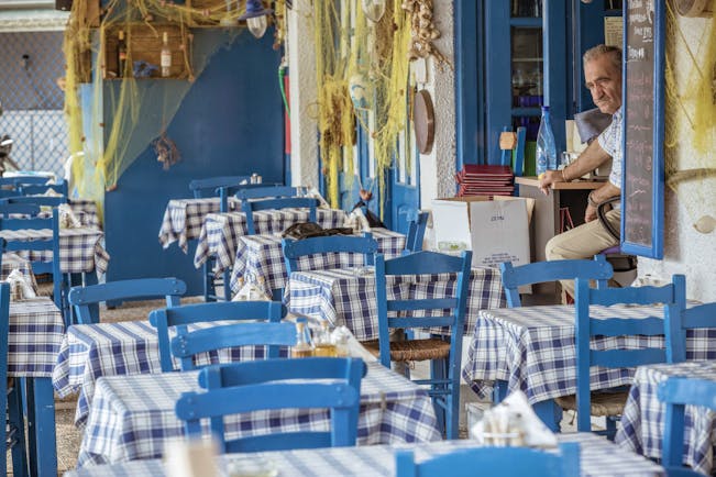 Restaurant seating area at the Skiathos Princess Hotel with blue painted wooden chairs and gingham table cloths covering the tables