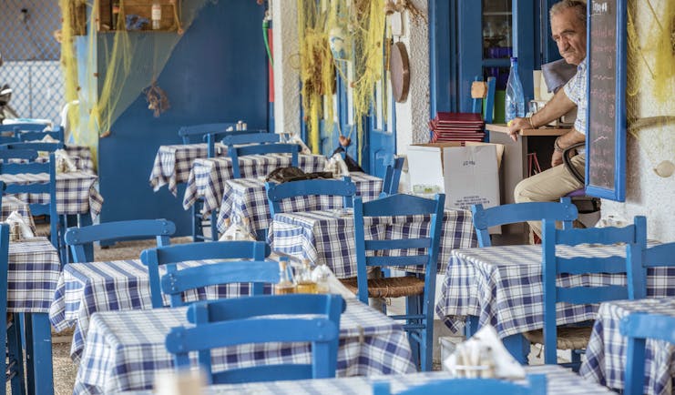 Restaurant seating area at the Skiathos Princess Hotel with blue painted wooden chairs and gingham table cloths covering the tables