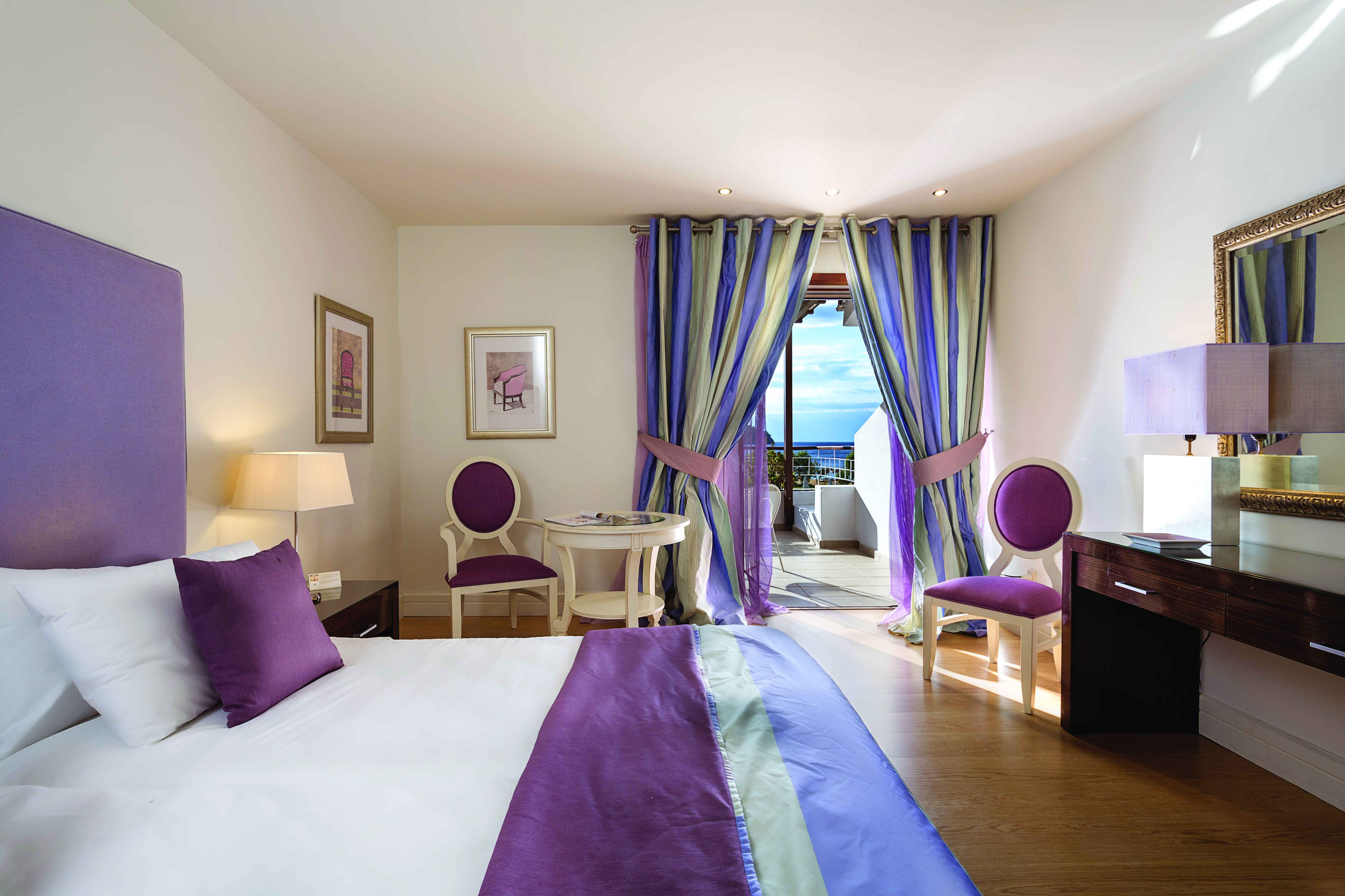 Suite at the Skiathos Princess Hotel  in Greece with large double bed, television, purple colour scheme and balcony with sea view 