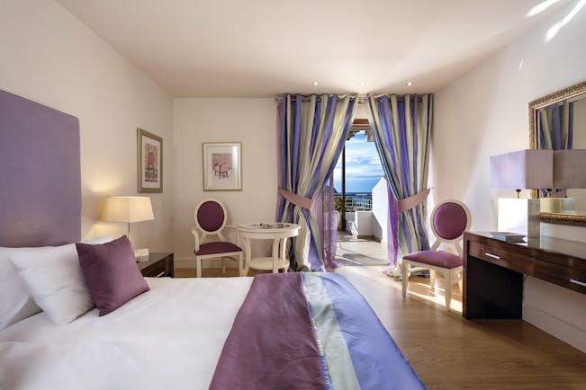 Suite at the Skiathos Princess Hotel  in Greece with large double bed, television, purple colour scheme and balcony with sea view 