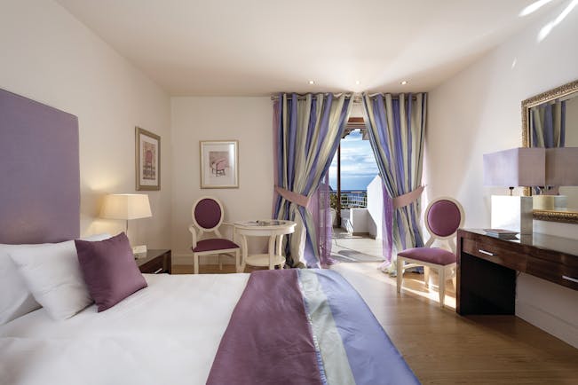 Suite at the Skiathos Princess Hotel  in Greece with large double bed, television, purple colour scheme and balcony with sea view 