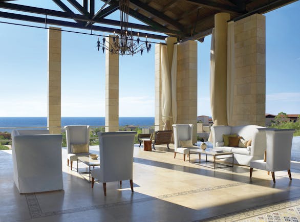 The Romanos Greece outdoor lobby with chairs and sofas