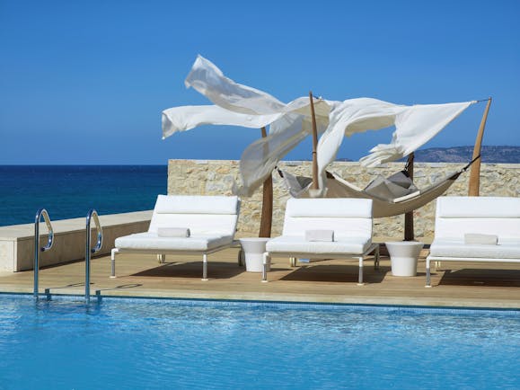 The Romanos Greece outside swimming pool with decked area with loungers and a hammock and sea view