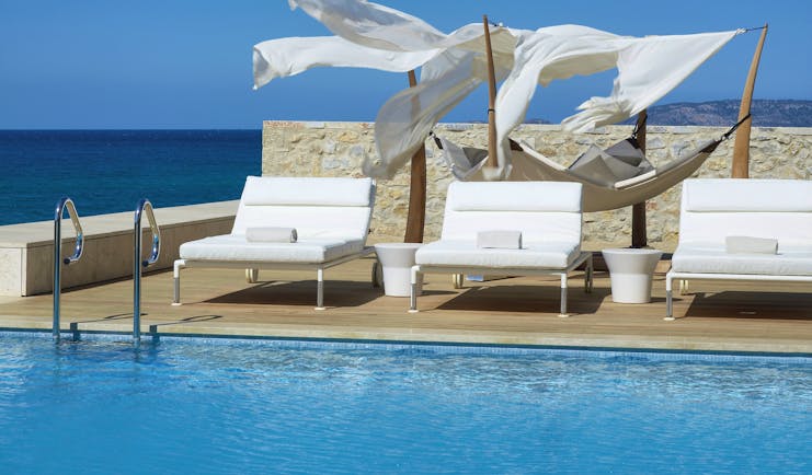 The Romanos Greece outside swimming pool with decked area with loungers and a hammock and sea view