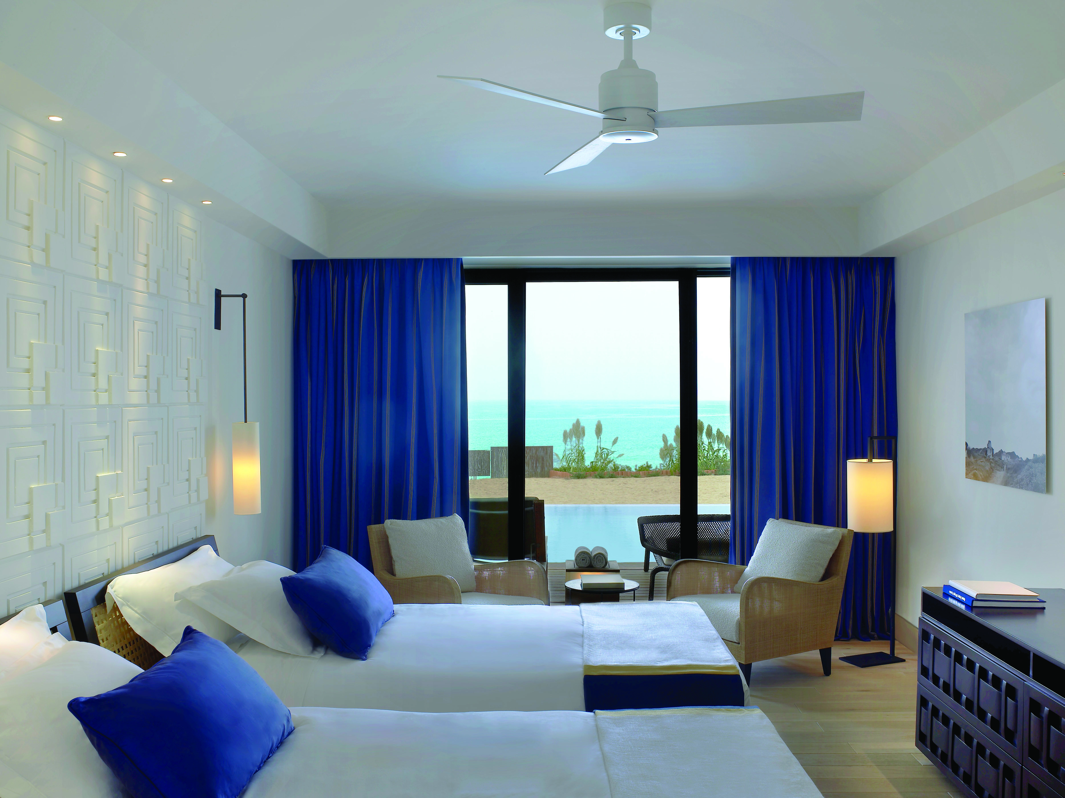 The Romanos Greece twin bedroom with blue curtains and patio doors to terrace