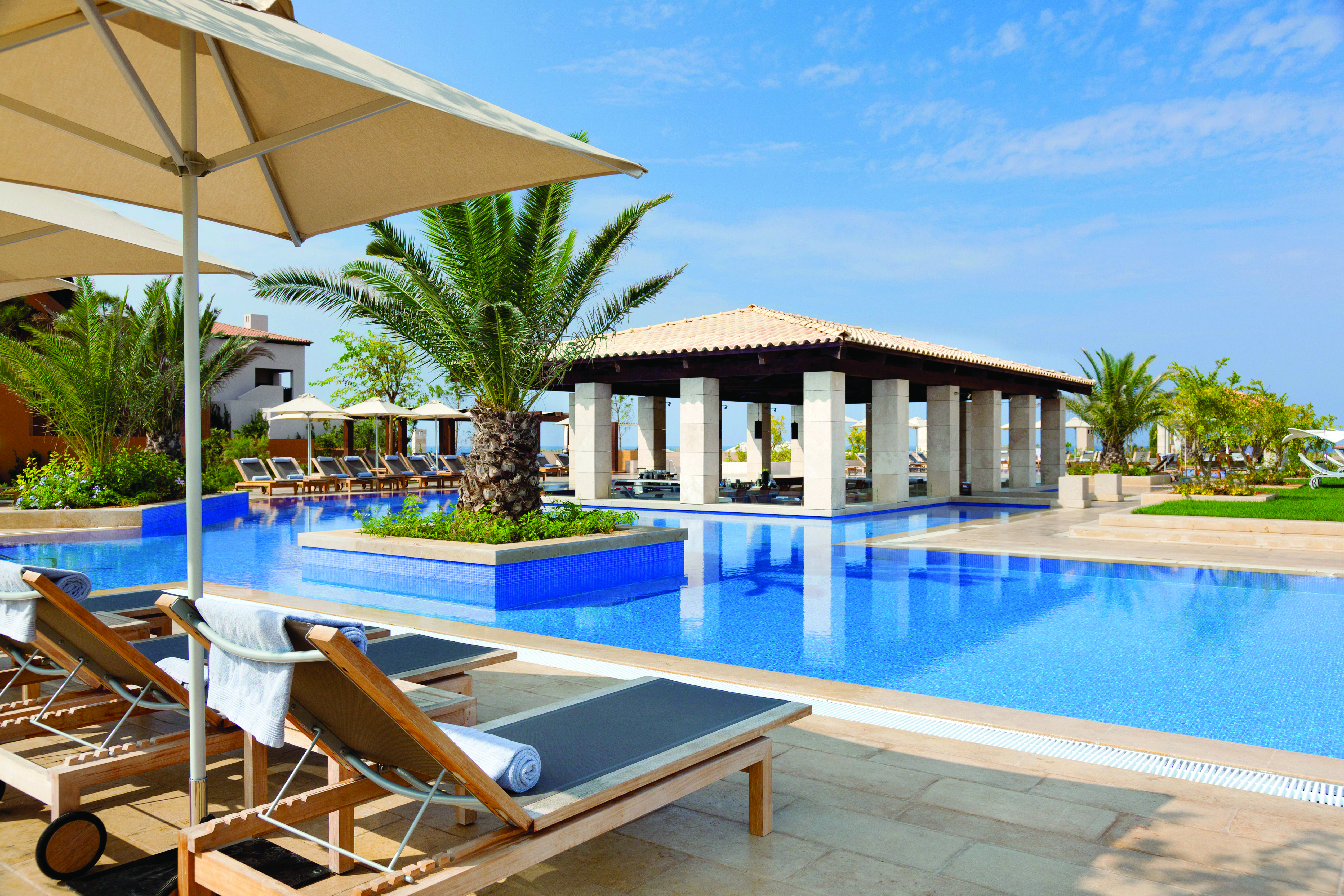 The Romanos Greece outdoor swimming pool with sun loungers and umbrellas 