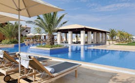 The Romanos Greece outdoor swimming pool with sun loungers and umbrellas 