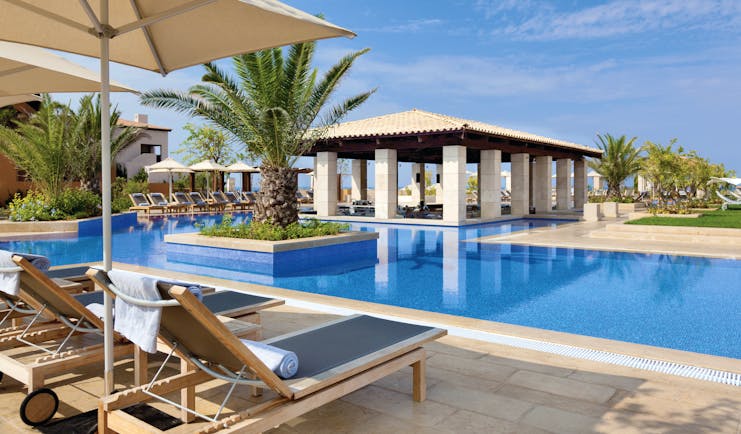 The Romanos Greece outdoor swimming pool with sun loungers and umbrellas 