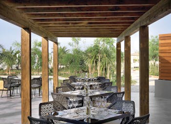 Outside dining area at the Westin Resort with black tables and chairs set out under a wooden roof