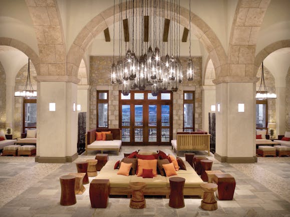 View of the Westin Resort lobby with big stone archways, pillars, a large, low hanging chandelier and cushioned seats 