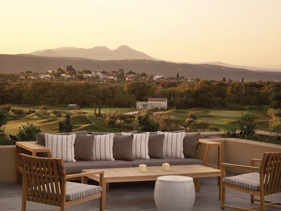 Outdoor lounge area at the Westin Resort with a benched seating area looking over to a mountain range covered by a yellow sunset