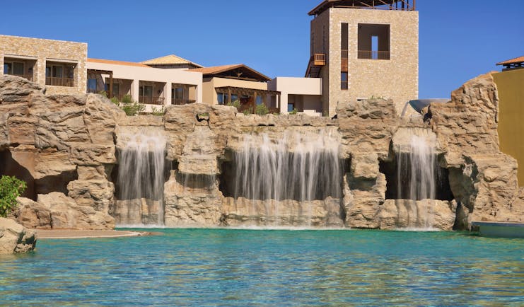 View of the outdoor pool with four waterfalls built into the rocks behind the pool