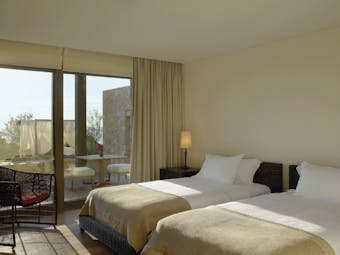 View of a twin room at the Westin Resort with two beds and a large window with doors opening onto a balcony