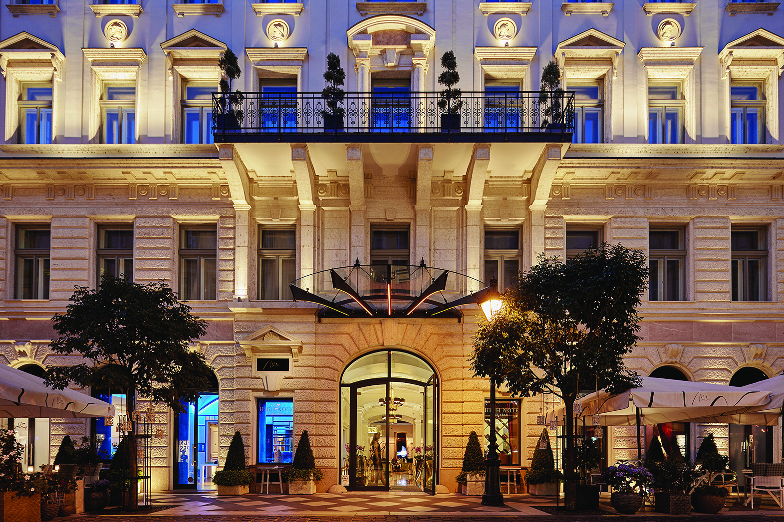 Aria Hotel Budapest exterior facade large cream stone building with a balcony and a ground floor terrace area