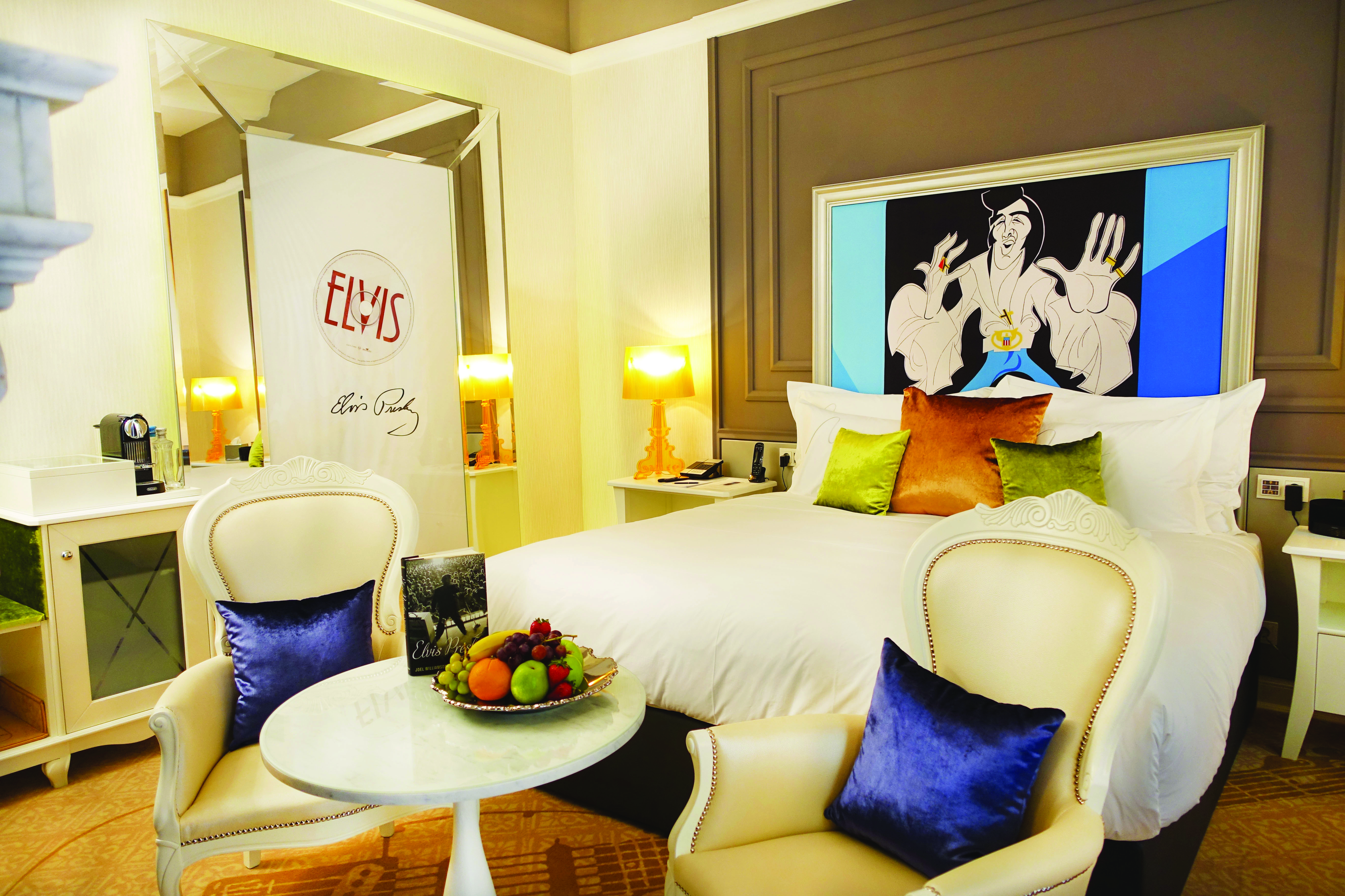 Aria Hotel Budapest luxury bedroom cartoon portrait of Elvis Presley large mirror and two blue and white chairs