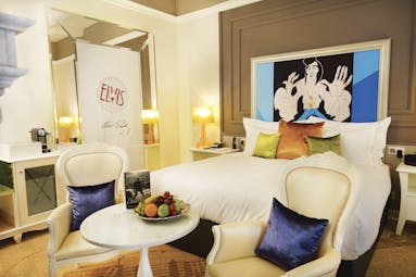 Aria Hotel Budapest luxury bedroom cartoon portrait of Elvis Presley large mirror and two blue and white chairs