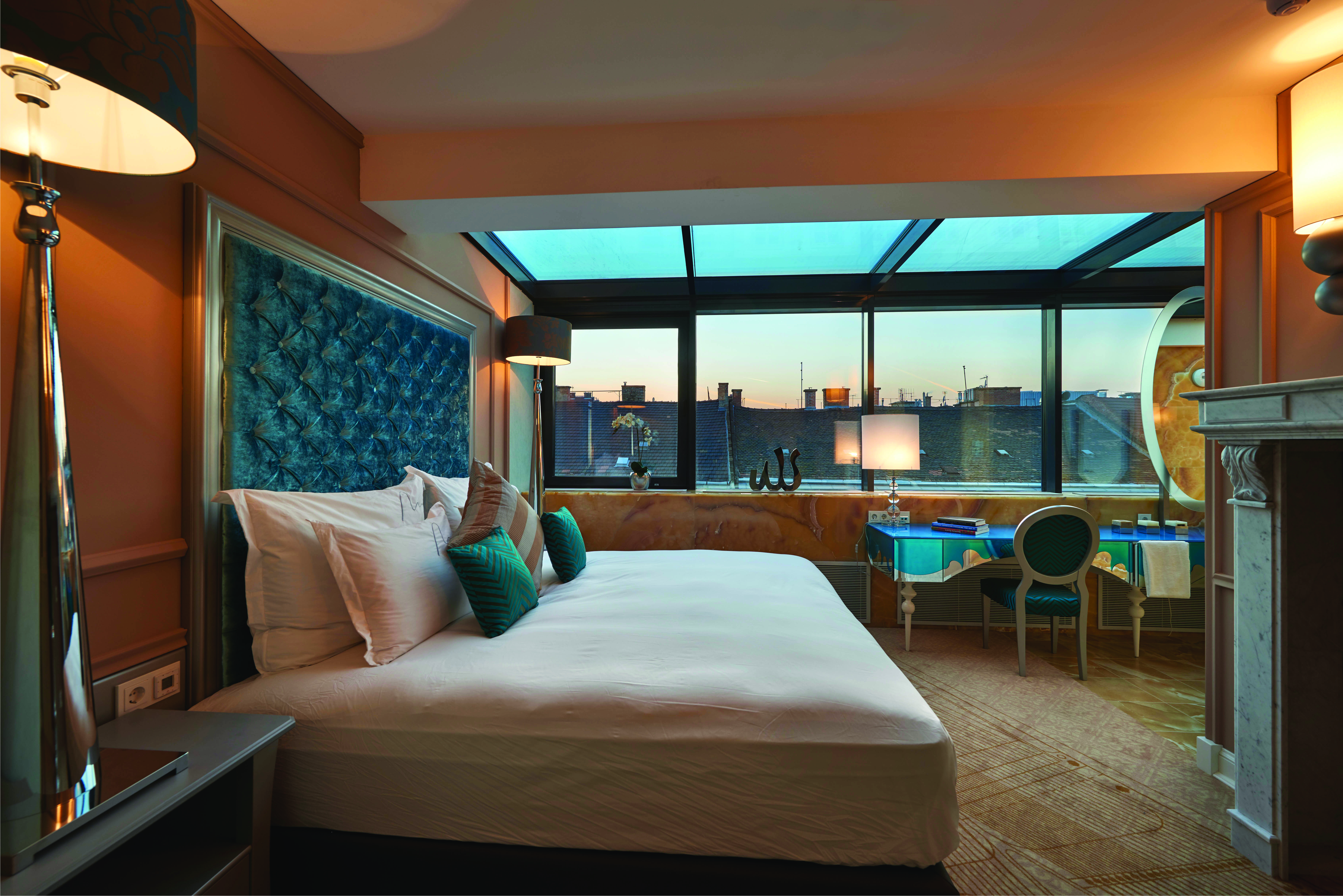 Aria Hotel Budapest suroom bed and blue desk chair and fireplace
