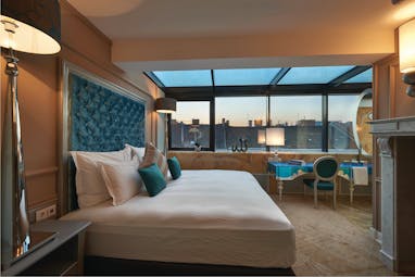 Aria Hotel Budapest suroom bed and blue desk chair and fireplace