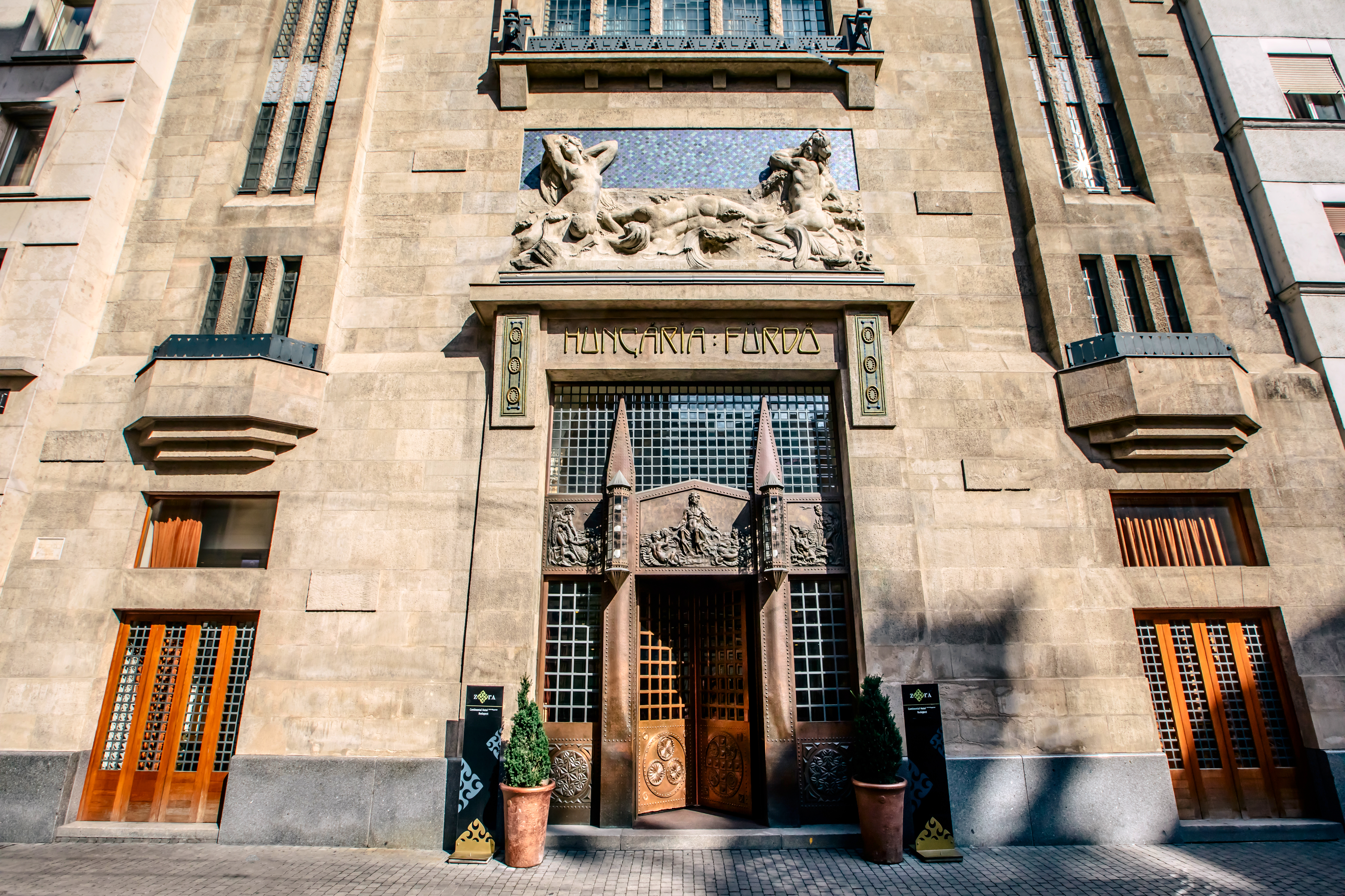 Continental Hotel entrance, stone wall with intricate wooden doors, statue on top
