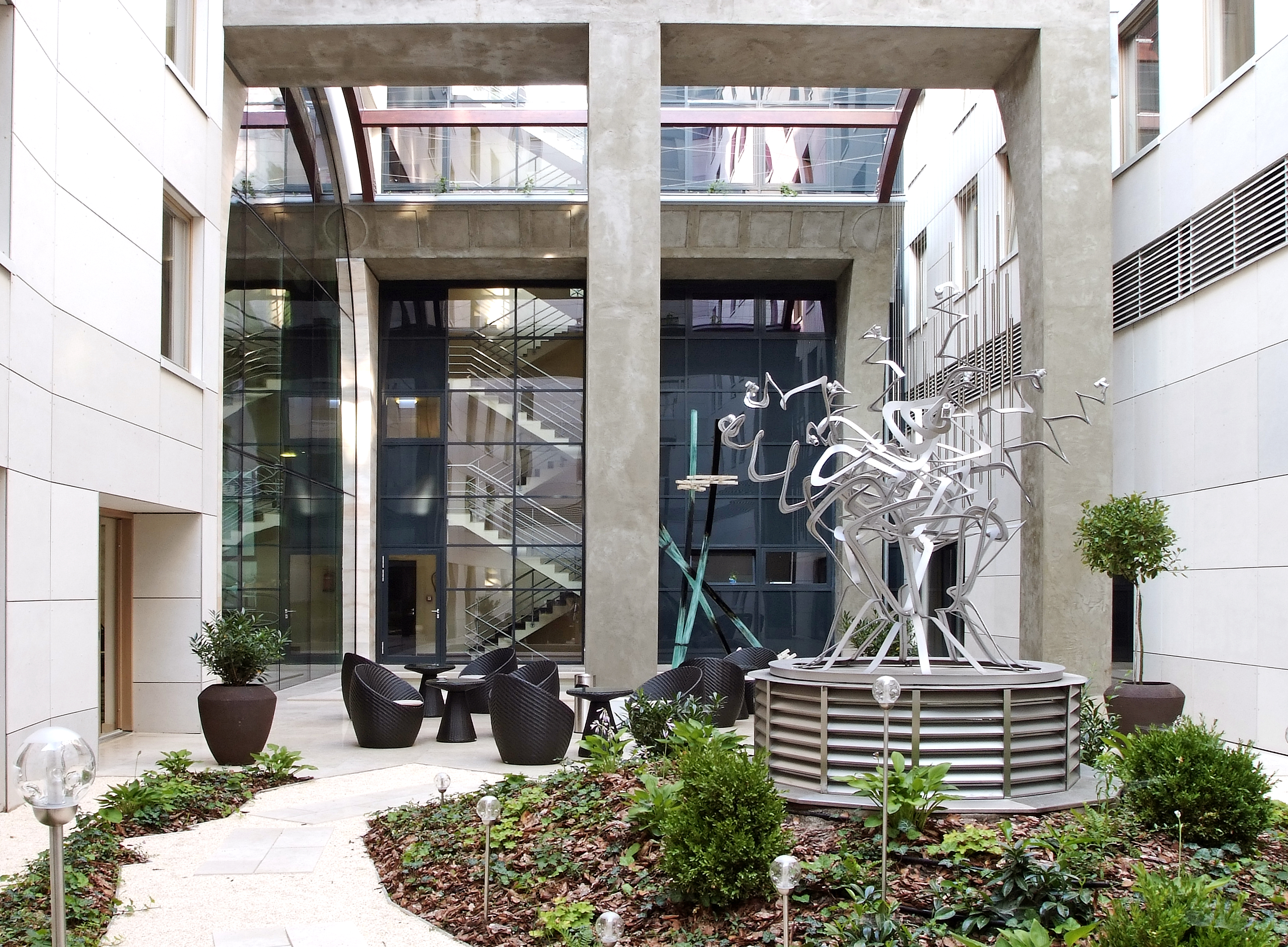 Continental Hotel courtyard garden, outdoor seating, flower beds, metal sculpture