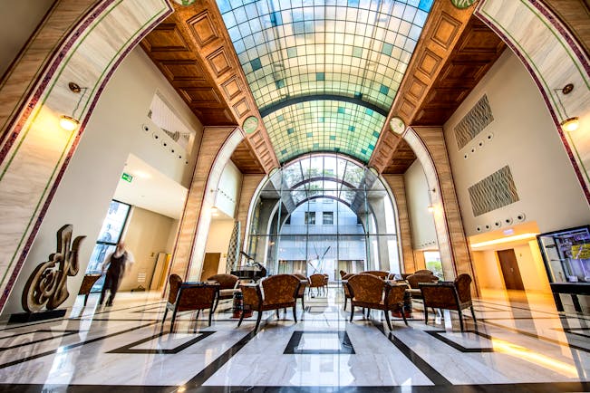 Continental Hotel lobby, art deco decor and architecture, glass arch shaped ceiling, marble floors, tables and chairs
