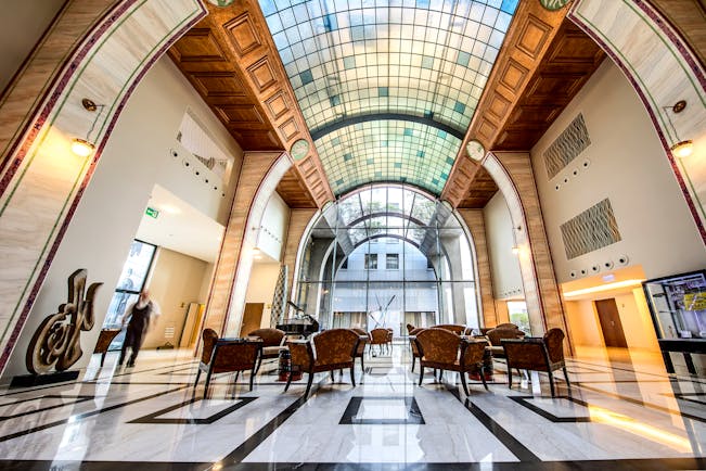 Continental Hotel lobby, art deco decor and architecture, glass arch shaped ceiling, marble floors, tables and chairs