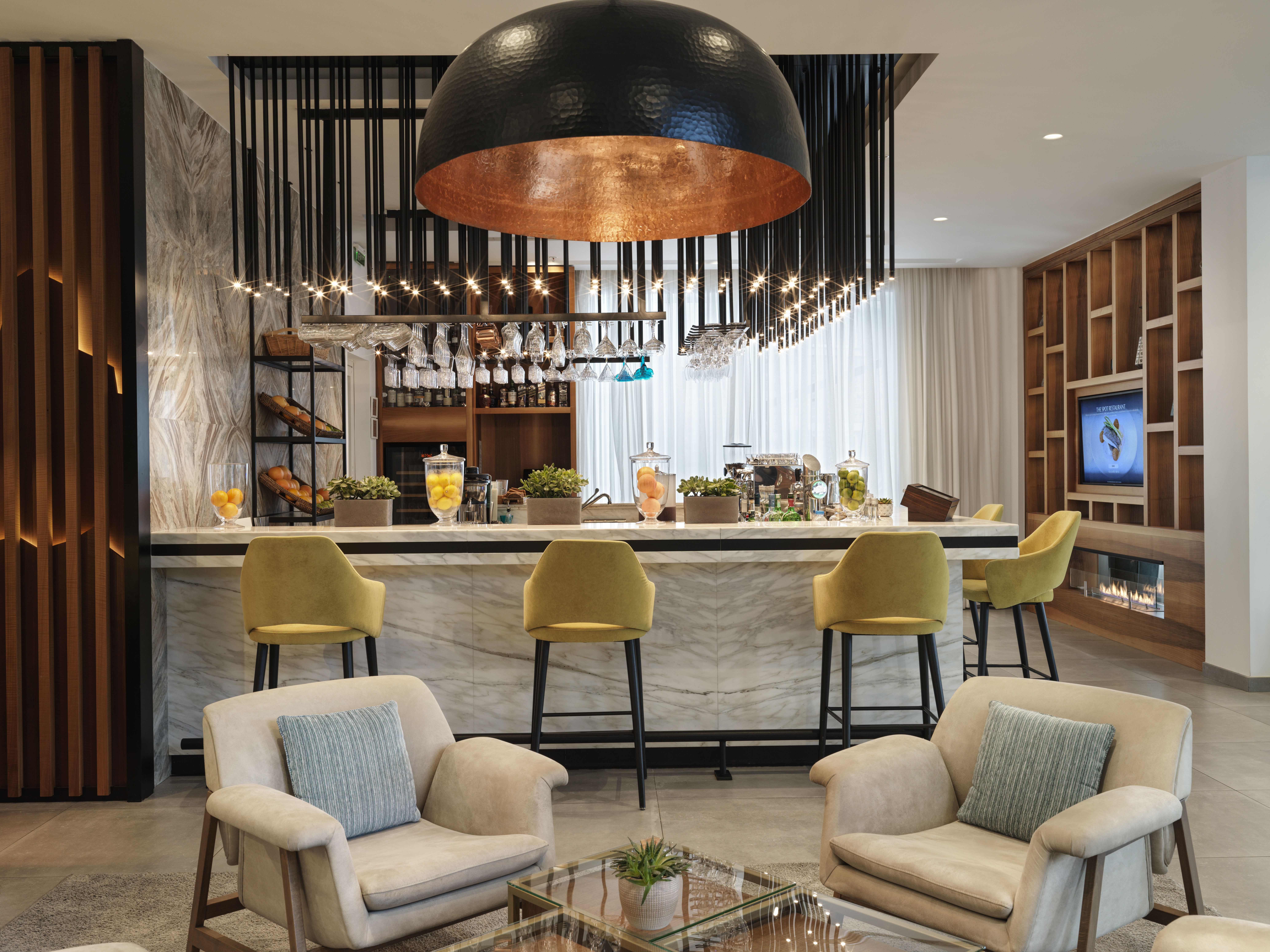 Chedi Lustica Bay bar with tall yellow stools, modern marble bar, and comfortable armchairs