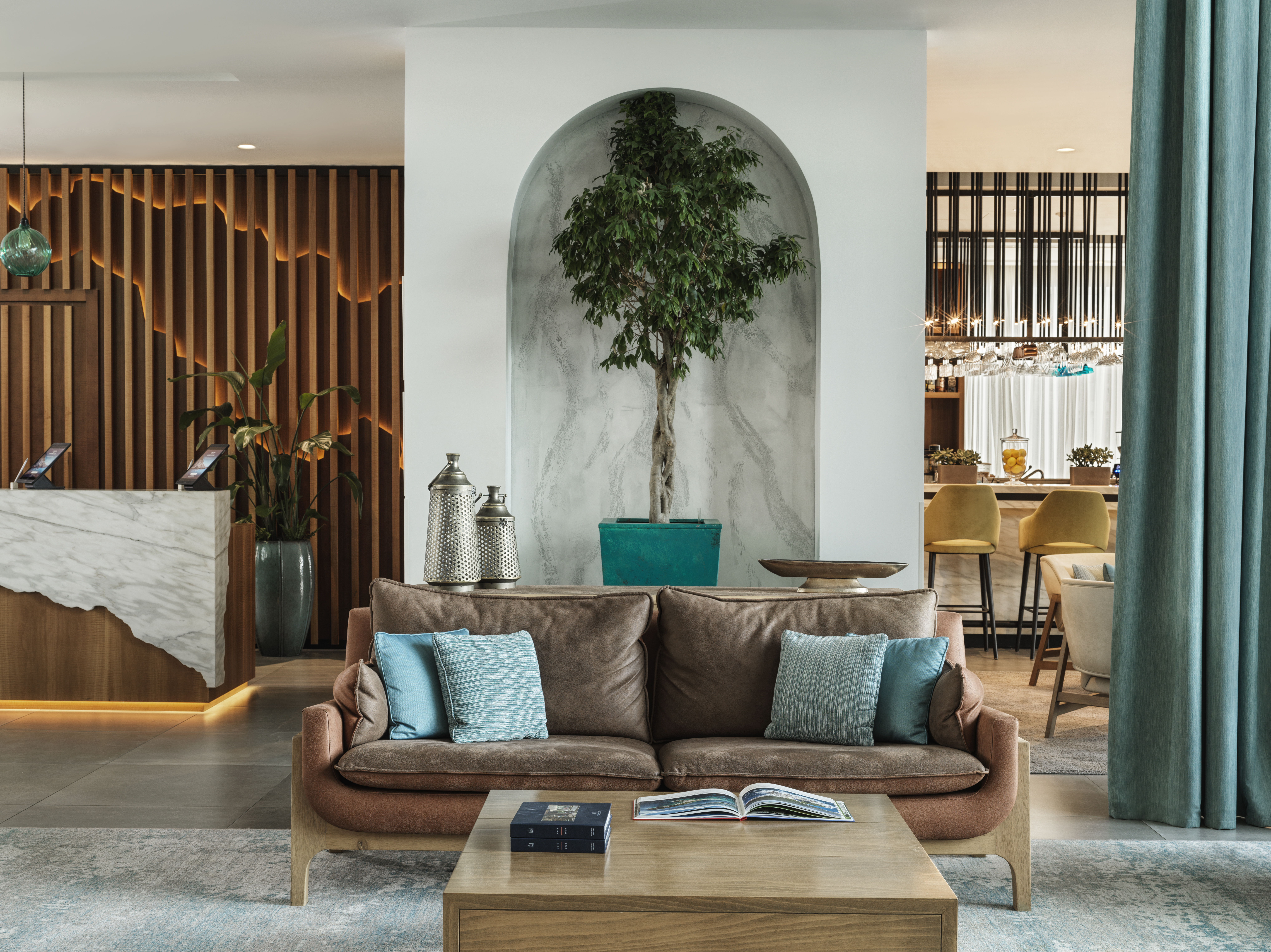 Chedi Lustica Bay lobby with marble floor, cosy sofa, blue curtains, and mountain-styled marble and wood reception desk