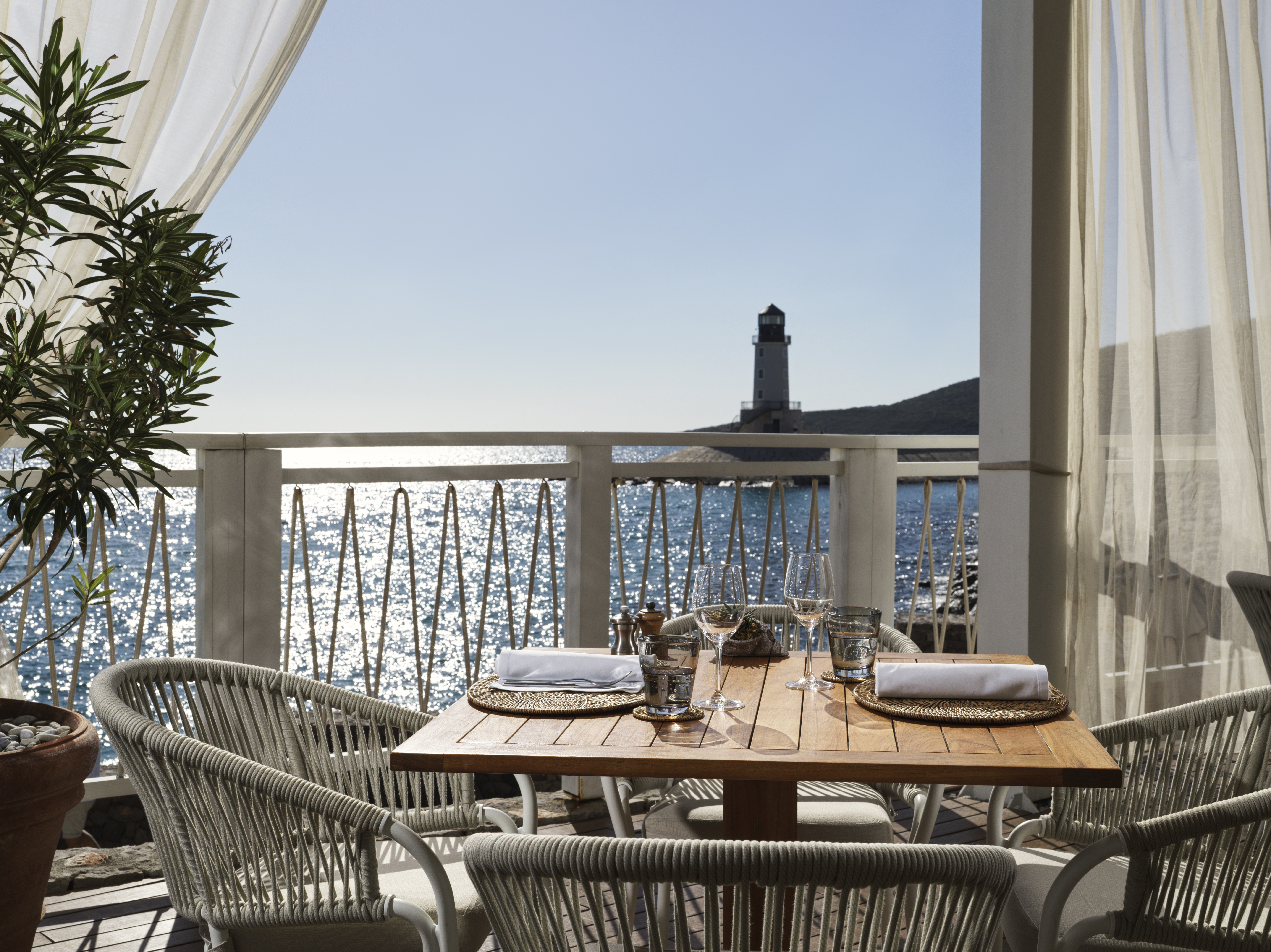 Chedi Lustica Bay terrace dining, with white rattan furnishings and stunning sea and lighthouse views