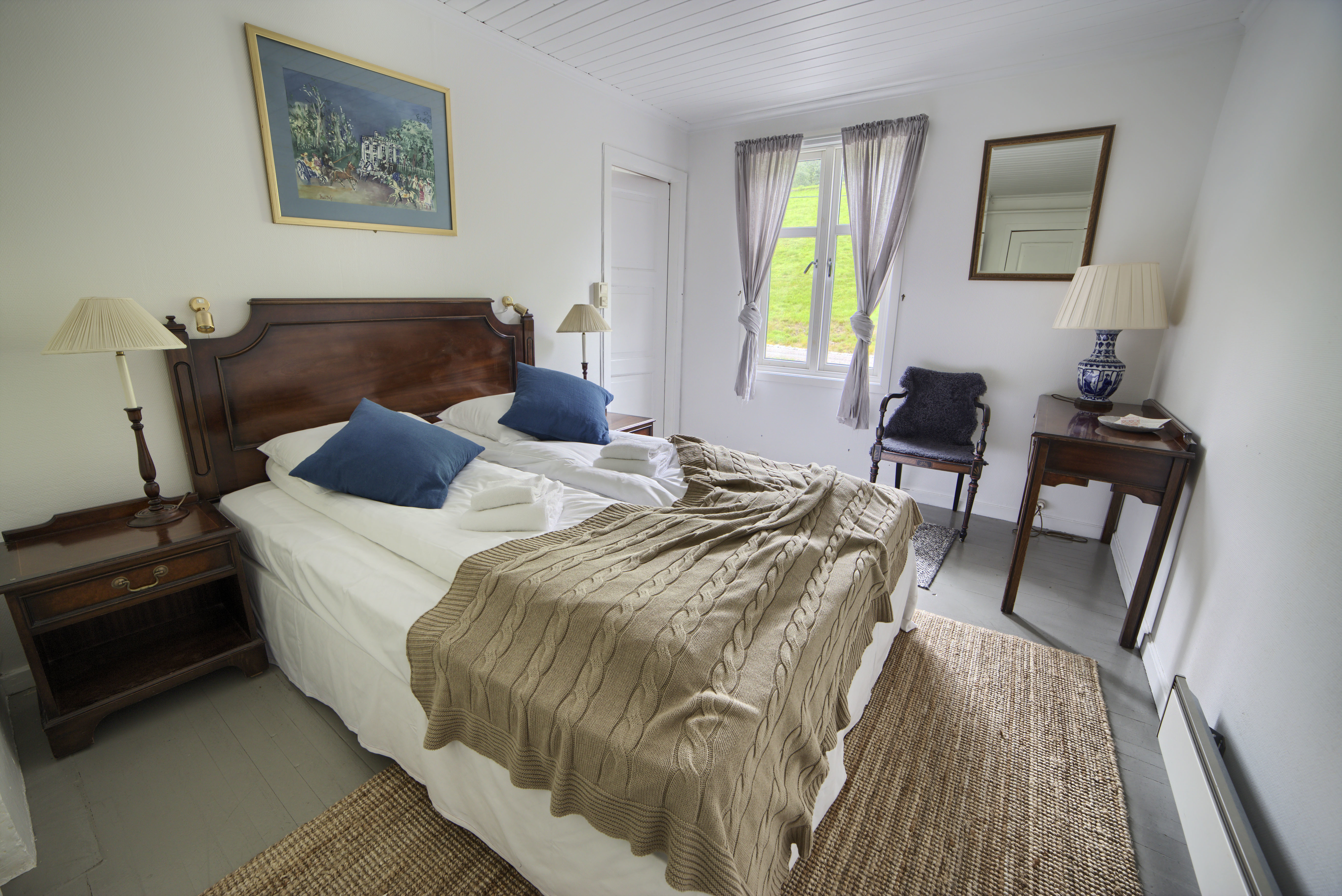 Fjaerland Fjordstove Hotell bedroom with blue cushions and picture over bed