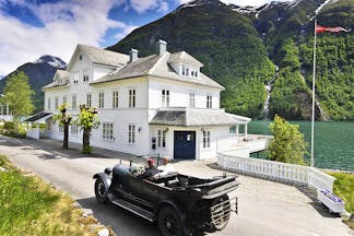 Fjaerland Fjordstove Hotell white hotel building on lake with vintage car in foreground